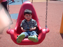 A child swinging on a special safety harness swing at the sensory playground at Fairmount park